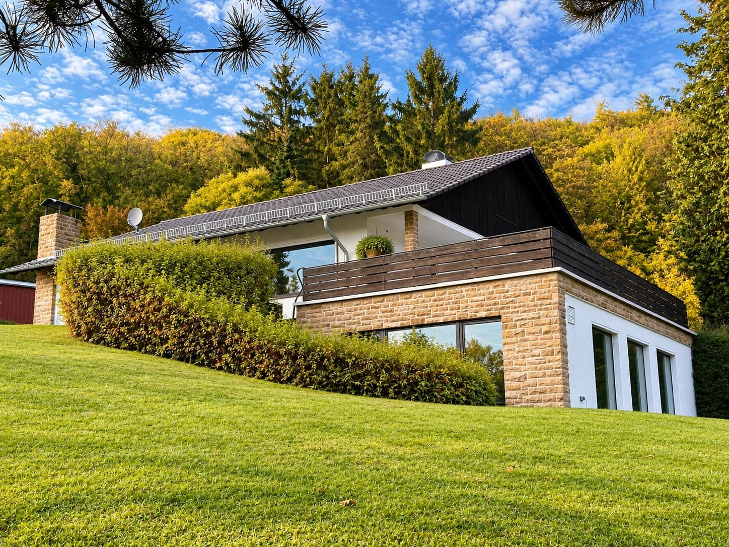 Haus am Hang mit Natursteinfassade und Terrasse über dem unteren Geschoss