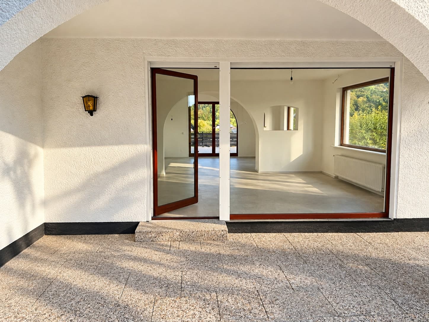 Blick von der Veranda durch die Glasfront in die leeren Innenräume
