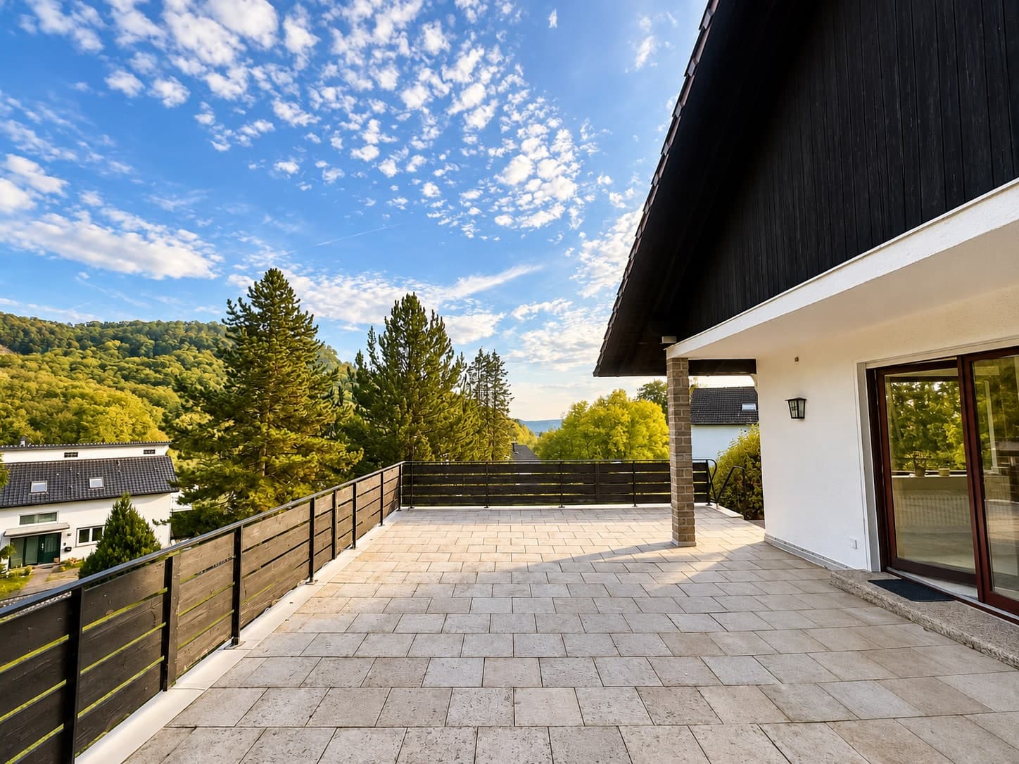 Terrasse entlang der Hausfassade mit Holzgeländer und Blick ins Grüne