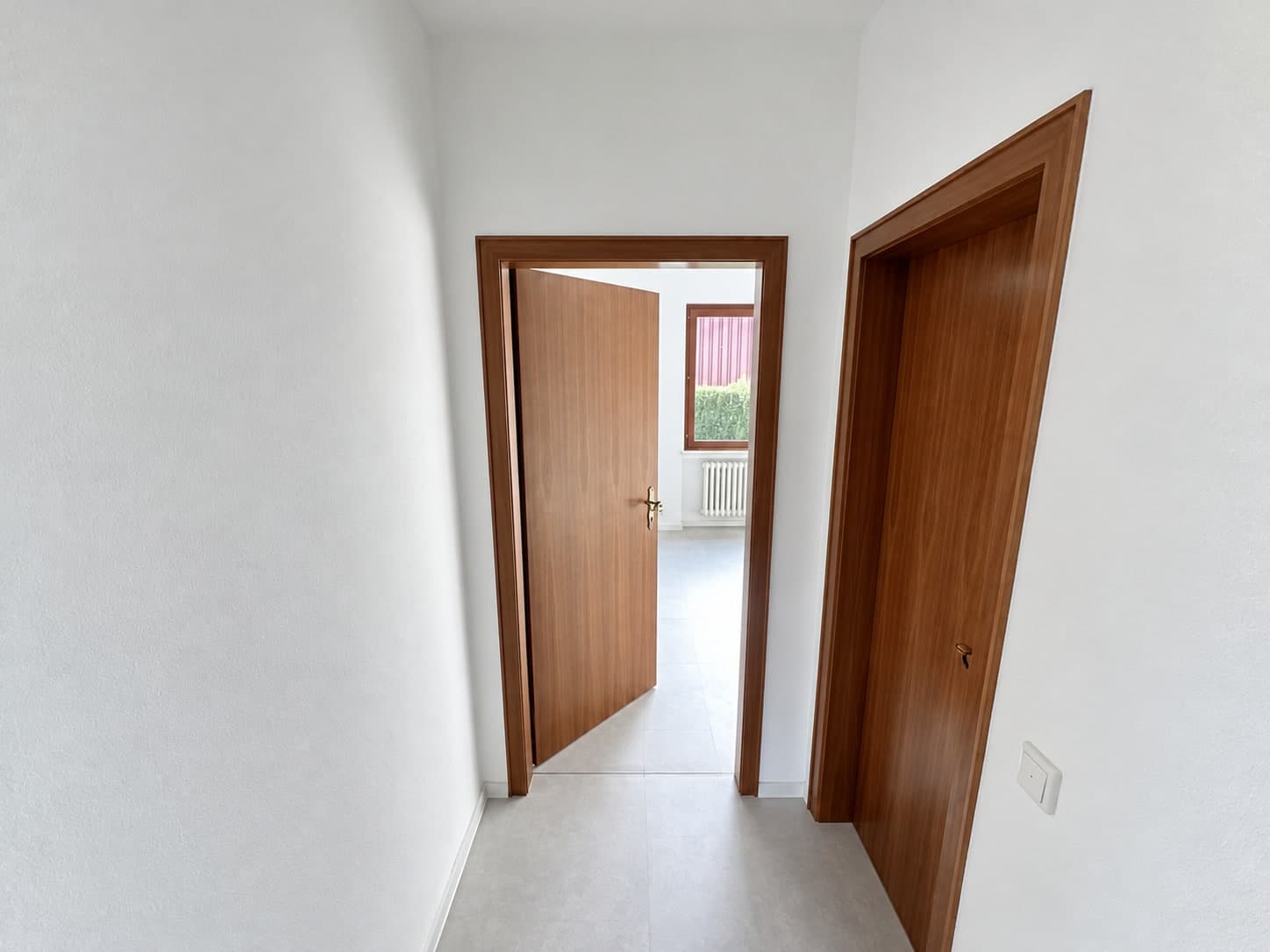 Heller schmaler Flur mit Holztüren und Blick in einen weiteren Raum