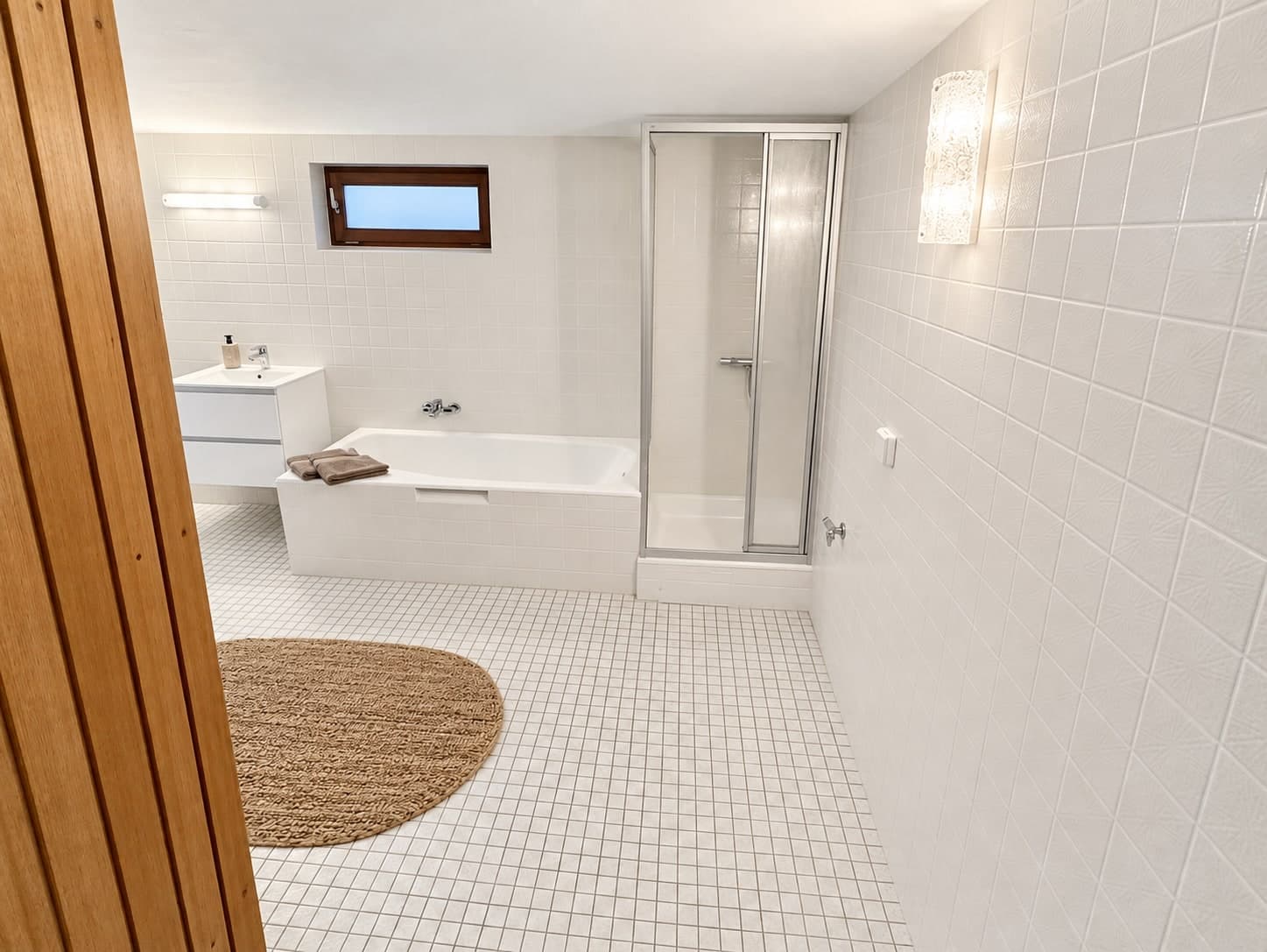 Hell gefliestes Badezimmer mit Badewanne, Duschkabine und Waschtisch